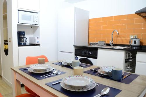 a kitchen with a table with plates and utensils at Casa en alquiler vacacional en Alcalá de Henares in Alcalá de Henares