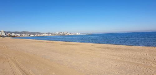 a sandy beach with the ocean and buildings in the background at Vacansis Habitaciones Privada en una Villa a un paso del Mar en Cullera in Cullera