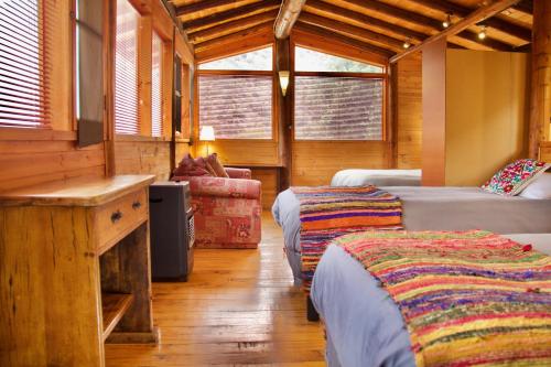 a bedroom with two beds and a desk in a cabin at Loft de montaña Los Guayacanes in San José de Maipo