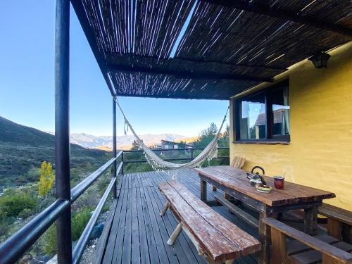 a wooden deck with a hammock and a wooden bench at Las Margaritas in Potrerillos