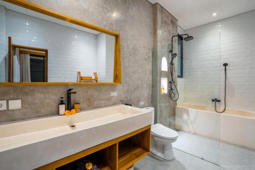 a bathroom with a tub and a sink and a toilet at The Kaba Kaba Private Luxury Villa in Tumbak Bayuh