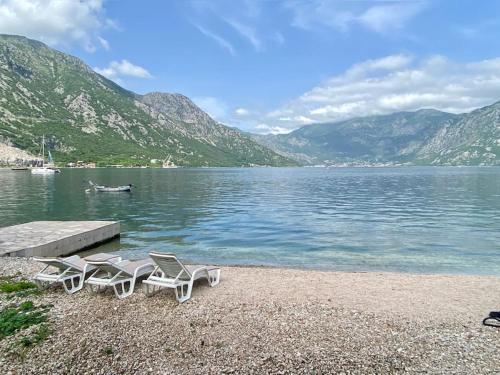 a group of chairs sitting on the shore of a lake at Lovely Beach House with Own Beach & SUP for Guests in Donji Morinj