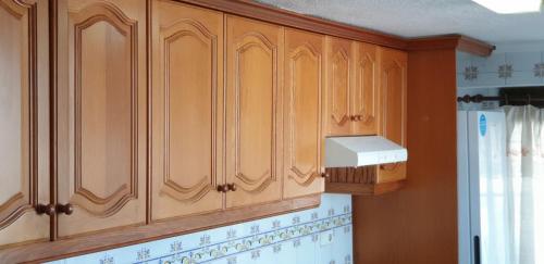 a kitchen with wooden cabinets and a box on the wall at Vacansis Habitaciones Privada en una Villa a un paso del Mar en Cullera in Cullera