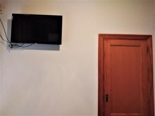 Une télévision à écran plat est installée sur un mur à côté d'une porte. dans l'établissement Habitaciones de Hostal a Primera linea de playa en Cullera, à Cullera