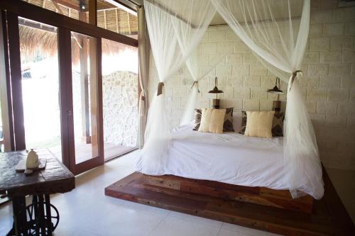 a bedroom with a bed with mosquito nets at La Cabane in Jimbaran