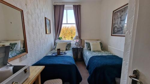 una camera d'albergo con due letti e uno specchio di The Ocean Guesthouse a Weymouth