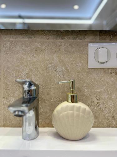 - un lavabo dans la salle de bains avec un distributeur de savon à côté d'un lavabo dans l'établissement La maison du Soleil, à Porticcio