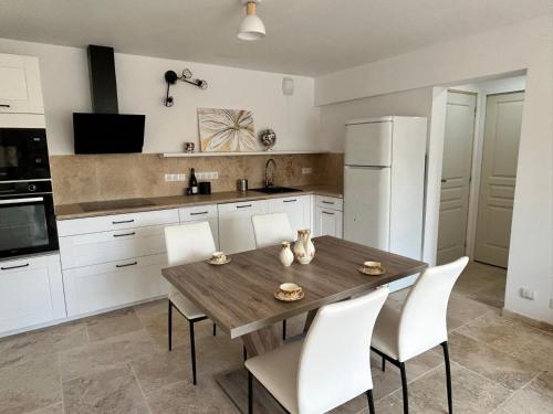 a kitchen with a wooden table and white appliances at La maison du Soleil in Porticcio