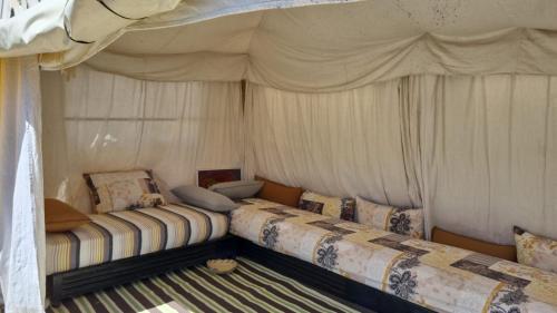 にあるMaison de campagne Benslimaneのカーテン付きの客室で、ベッド2台が備わります。