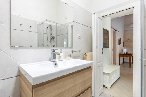 ein weißes Badezimmer mit einem Waschbecken und einem Spiegel in der Unterkunft Hostly-Garden House San Lorenzo-Few steps to Tower in Pisa