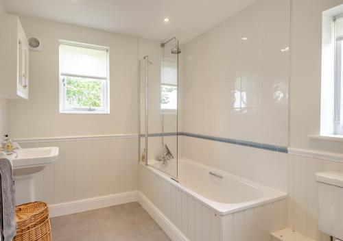 a white bathroom with a tub and a sink at Lodge Farm Cottage in Sudbourne