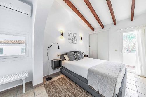 a white bedroom with a bed and a window at Villa Monsy 2 in El Port
