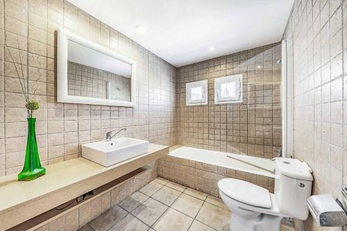 a bathroom with a toilet and a sink and a tub at Villa Monsy 2 in El Port