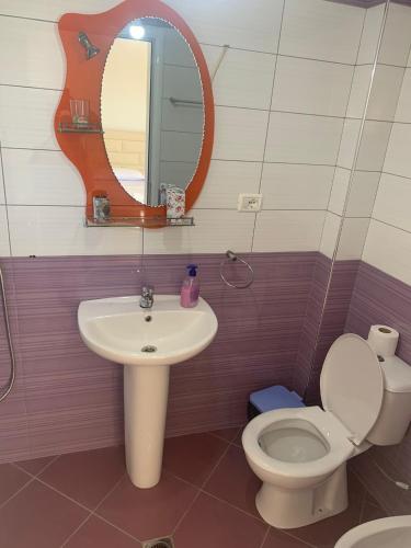 a bathroom with a sink and a toilet and a mirror at A 3-floor building with 4 bedroom near beach in Fier