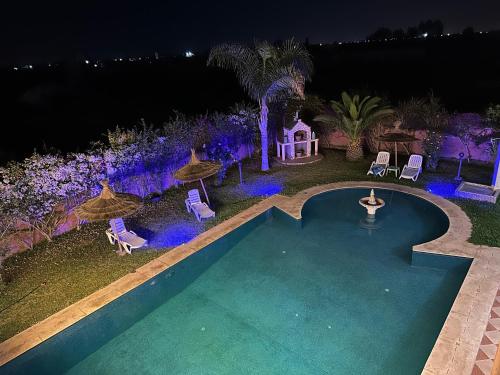 einen Pool mit Stühlen und einem Pavillon in der Nacht in der Unterkunft Marrakech Luxury Villa Farm in Marrakesch