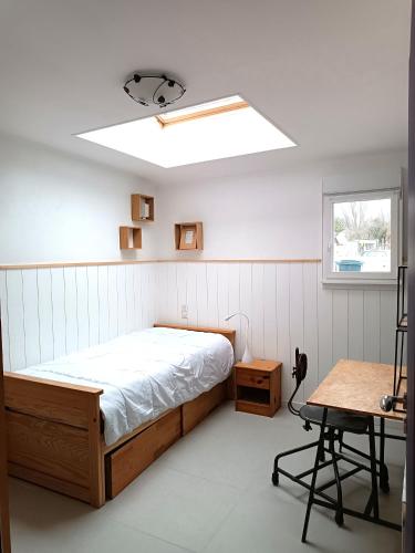 une chambre avec un lit, une fenêtre et une table dans l'établissement maison l'été à la plage, à Larmor-Plage