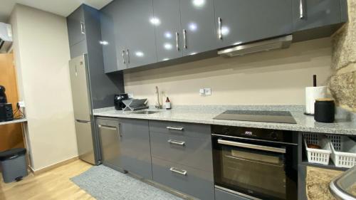 a kitchen with gray cabinets and a stove top oven at Casa do Miradouro Mondim de Basto in Mondim de Basto