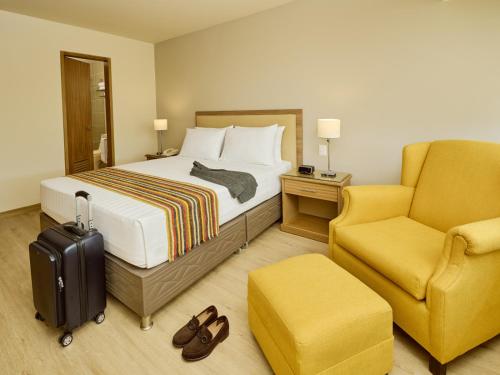 Habitación de hotel con cama y silla en Estelar Apartamentos Bellavista, en Lima
