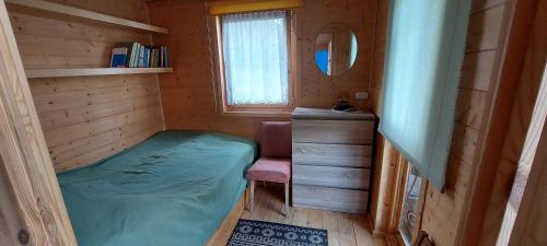 a small room with a bed and a mirror at Lemanka Domek Letniskowy in Gowidlino