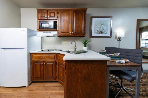 a kitchen with wooden cabinets and a white refrigerator at Extended Stay Airport in Green Bay