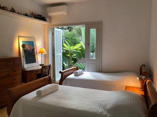 a bedroom with two beds and a window with a view at Charmosa casa 4 suítes no Jd Europa in Sao Paulo