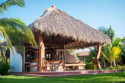 a hut with a table and chairs and palm trees at El MURO MAJAHUA RETREAT CENTER in La Majahua