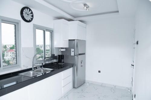 cocina blanca con fregadero y reloj en la pared en El Residanciel Palmiers 1, en Douala