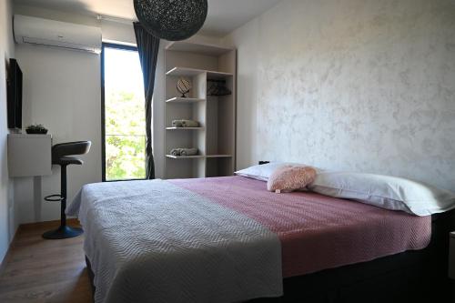 a bedroom with a bed with a pink blanket and a window at Apartmani Vito in Biograd na Moru