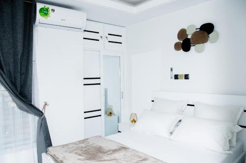 1 dormitorio con paredes blancas y 1 cama con almohadas blancas en El Residanciel Palmiers 1, en Douala