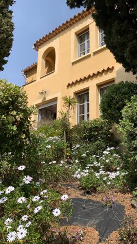 une maison jaune avec des fleurs devant elle dans l'établissement Clair de Lune, à Rayol-Canadel-sur-Mer