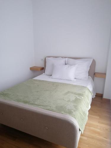 a bed with white pillows and a green blanket at Apartamento Mar-Azul in Laxe