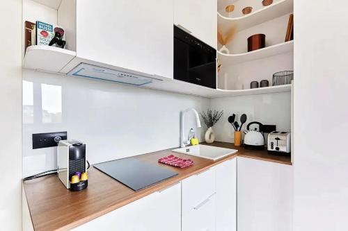 une cuisine blanche avec un évier et un micro-ondes dans l'établissement Studio charmant à Paris, près de l'Arc de Triomphe, à Paris