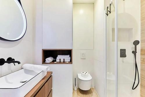 une salle de bain blanche avec une douche et un lavabo dans l'établissement Studio charmant à Paris, près de l'Arc de Triomphe, à Paris