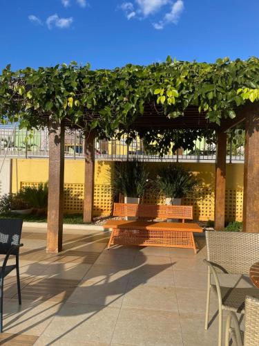 a patio with orange benches under a pergola at Apartamento caldas novas in Caldas Novas