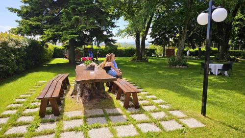 a woman sitting at a picnic table in a park at HOTEL AI TIGLI in Langhirano