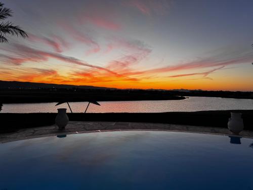 a sunset over the water with a table with an umbrella at Sunset Villa in El Gouna with Private Heated Pool NEW BEDROOMS ADDED in Hurghada