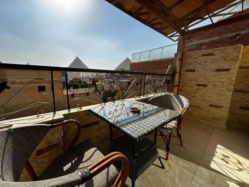 a table and chairs on a balcony with a view at Narmer Pyramids View in Cairo