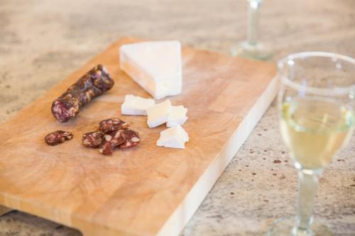 a cutting board with cheese and nuts and a glass of wine at Tolmin Center Apartments Townhouse & Loft in Tolmin