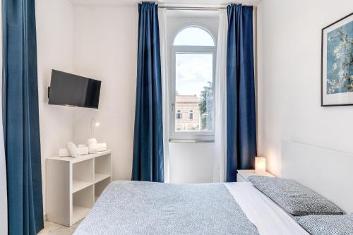 a bedroom with a bed with blue curtains and a window at V E N E R E Apartments in Rome