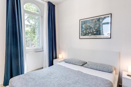 a bedroom with a bed with blue curtains and a window at V E N E R E Apartments in Rome