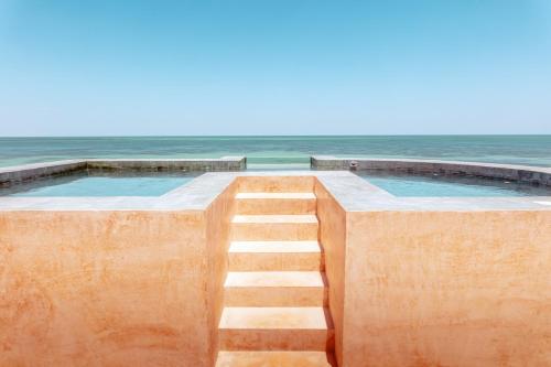a staircase leading to a swimming pool next to the ocean at AWA Holbox Hotel Boutique - Beach Front in Holbox Island
