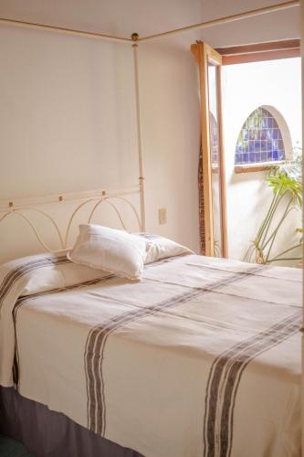 a bedroom with a bed with white sheets and a window at El MURO MAJAHUA RETREAT CENTER in La Majahua