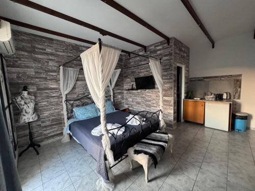 SunnySun Studios في فاليراكي: غرفة نوم بسرير مظلة وجدار حجري