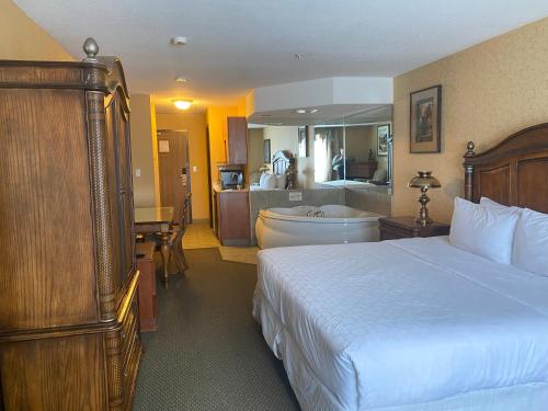 a bedroom with a bed and a bathroom with a tub at Merit Hotel & Suites in Fort McMurray
