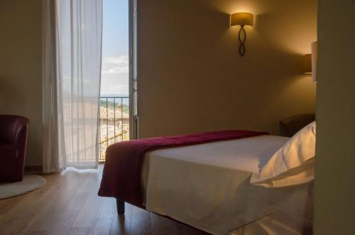 a bedroom with a bed and a large window at Antico Sipario Boutique Hotel, BW Signature Collection in Paciano