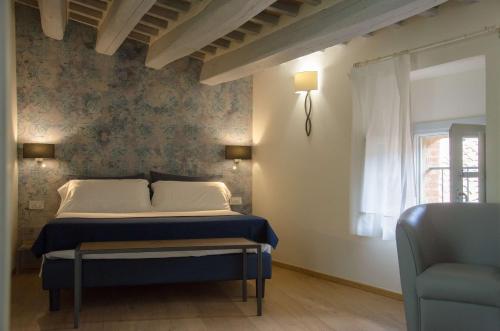 a bedroom with a bed and a window and a chair at Antico Sipario Boutique Hotel, BW Signature Collection in Paciano