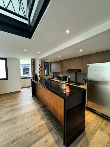 a kitchen with a black counter and a refrigerator at Calzolli Penthouse Casa de Huéspedes y Coliving in Mexico City