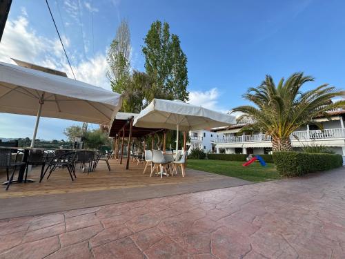 a patio with tables and chairs and umbrellas at Regos Resort Hotel in Neos Marmaras