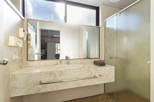 ein Bad mit einem Waschbecken und einem Spiegel in der Unterkunft Baronga Motor Inn in Colac