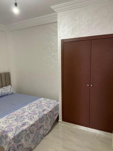 a bedroom with a bed and a brown cabinet at Rhach alhoceima in Al Hoceïma